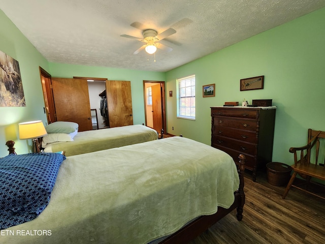 bedroom with a textured ceiling, ceiling fan, and dark hardwood / wood-style flooring