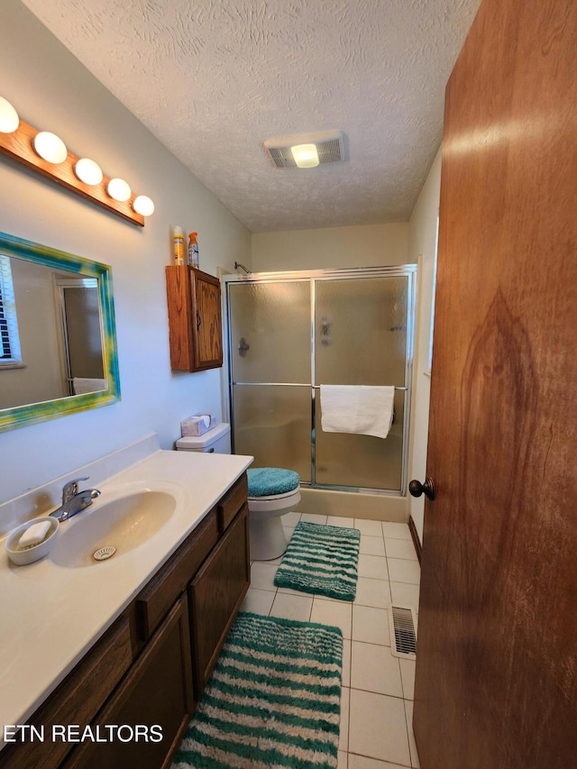 bathroom featuring a shower with door, a textured ceiling, toilet, vanity, and tile patterned flooring