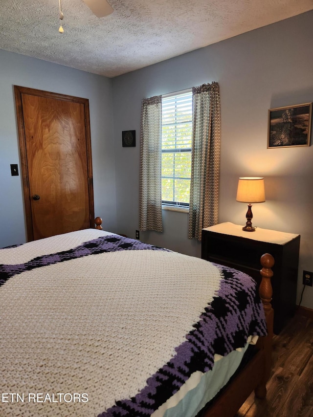 bedroom with ceiling fan, a textured ceiling, and dark hardwood / wood-style flooring