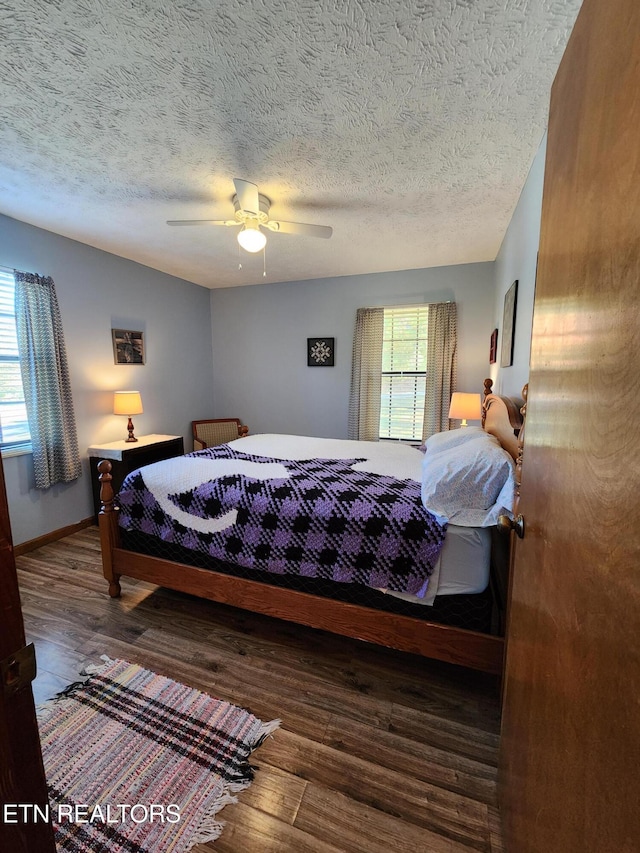 bedroom with a textured ceiling, wood-type flooring, and ceiling fan