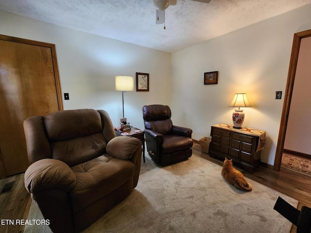 sitting room featuring ceiling fan, a textured ceiling, and light hardwood / wood-style flooring