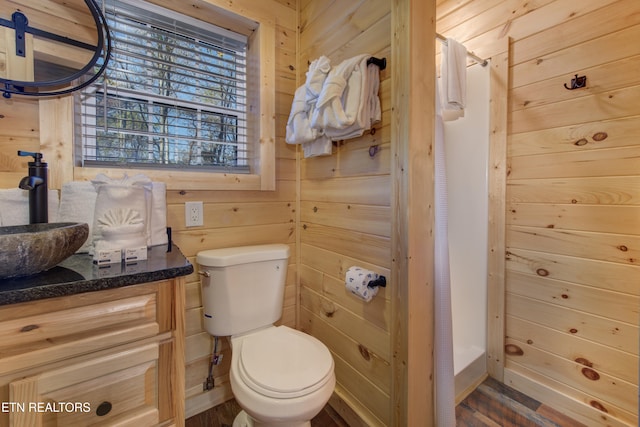 bathroom with a shower with shower curtain, vanity, toilet, and wooden walls