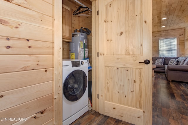 clothes washing area with washer / clothes dryer, water heater, dark wood-type flooring, and wood walls