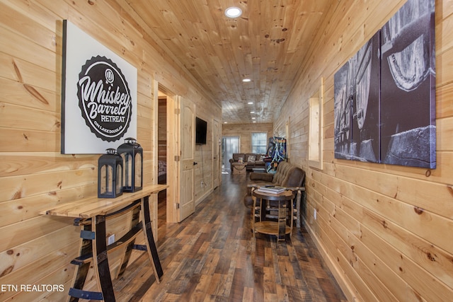 hall with dark hardwood / wood-style floors, wooden ceiling, and wooden walls