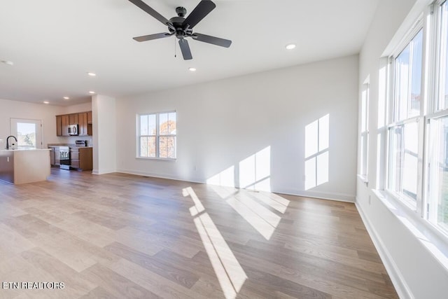 unfurnished living room with ceiling fan, a healthy amount of sunlight, and light hardwood / wood-style flooring