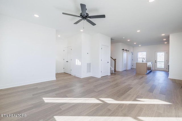 unfurnished living room with light wood-type flooring, ceiling fan, and sink