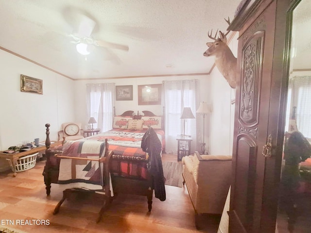 bedroom featuring ornamental molding, wood-type flooring, ceiling fan, and a textured ceiling