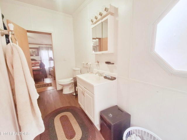 bathroom with toilet, vanity, hardwood / wood-style flooring, and crown molding