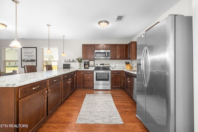 kitchen featuring hanging light fixtures, stainless steel appliances, dark wood-type flooring, and plenty of natural light