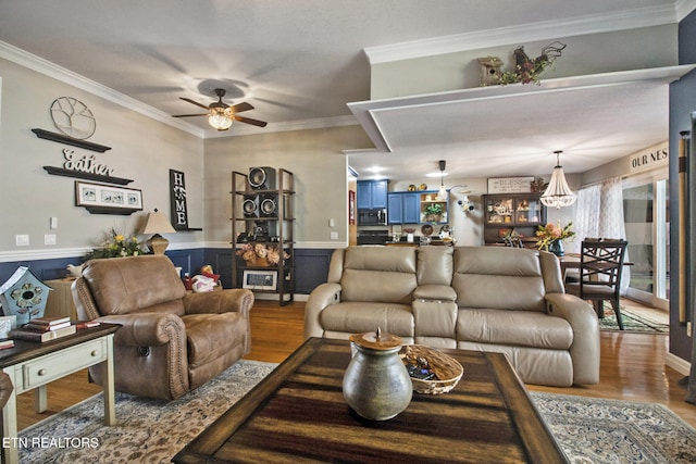 living room featuring ornamental molding, hardwood / wood-style flooring, and ceiling fan with notable chandelier