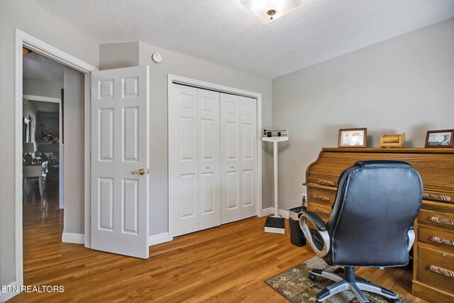 home office featuring hardwood / wood-style floors and a textured ceiling