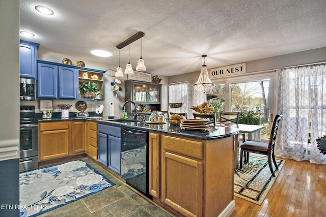 kitchen featuring kitchen peninsula, stainless steel appliances, dark wood-type flooring, sink, and decorative light fixtures