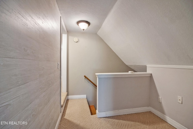 stairs with vaulted ceiling, a textured ceiling, and carpet floors