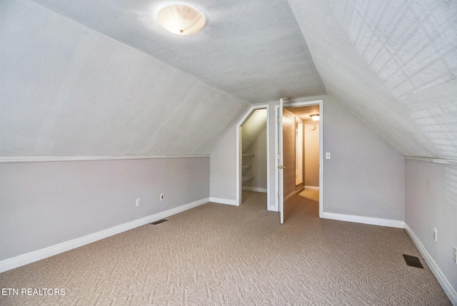 bonus room featuring a textured ceiling, carpet, and lofted ceiling