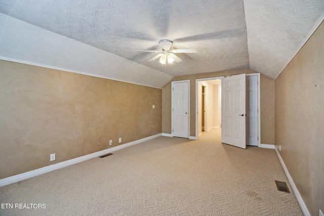 additional living space featuring ceiling fan, a textured ceiling, vaulted ceiling, and light colored carpet