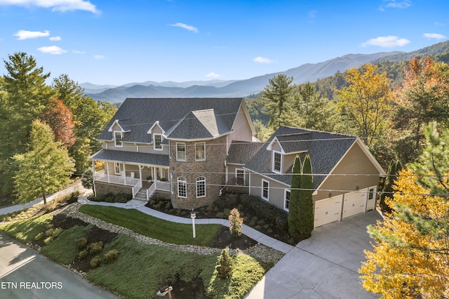 exterior space with covered porch, a garage, a mountain view, and a front lawn