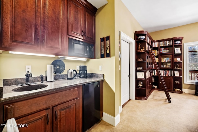 kitchen featuring light carpet, dark stone countertops, sink, and black fridge