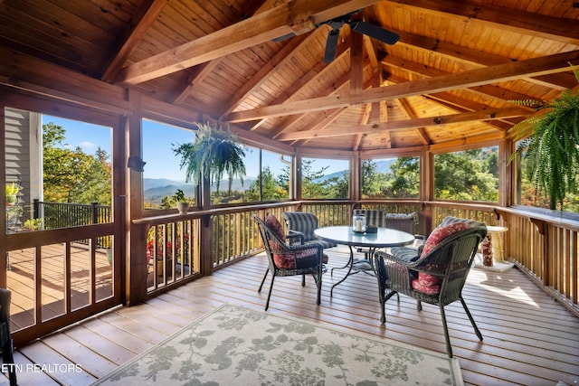 sunroom with vaulted ceiling with beams, wood ceiling, a mountain view, and ceiling fan