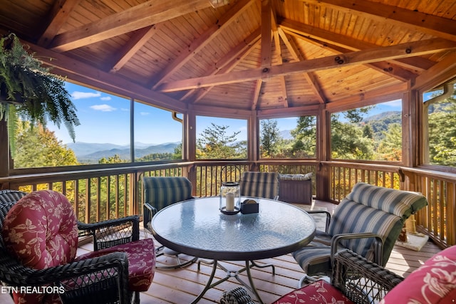 sunroom with a mountain view, lofted ceiling with beams, and wooden ceiling