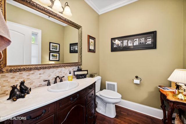 bathroom featuring decorative backsplash, hardwood / wood-style flooring, toilet, crown molding, and vanity