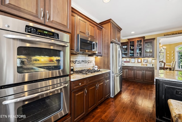 kitchen with backsplash, dark hardwood / wood-style flooring, stainless steel appliances, light stone counters, and ornamental molding