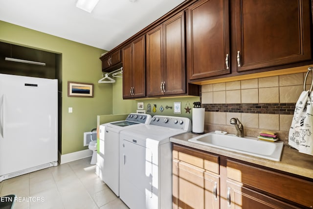 washroom featuring sink, light tile patterned flooring, washer and dryer, and cabinets