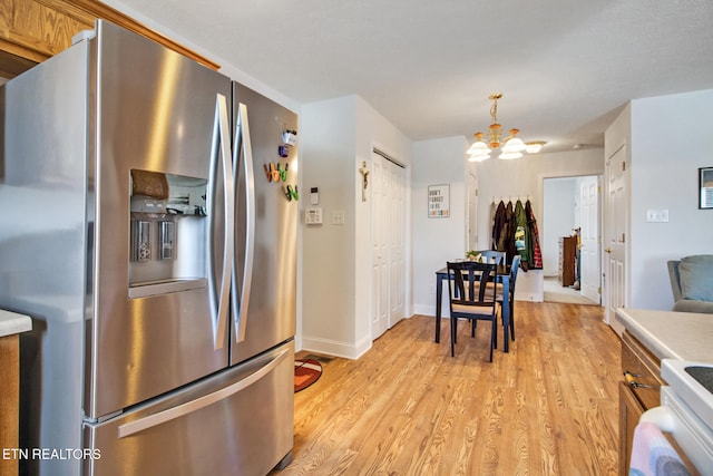 kitchen featuring light hardwood / wood-style flooring, hanging light fixtures, stainless steel fridge with ice dispenser, a chandelier, and white stove