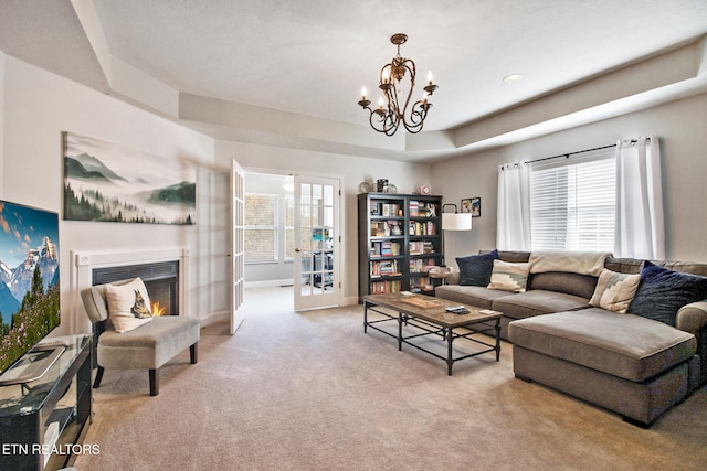 living room featuring a notable chandelier, light colored carpet, and a tray ceiling