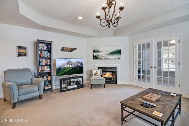 carpeted living room featuring french doors, a chandelier, and a raised ceiling