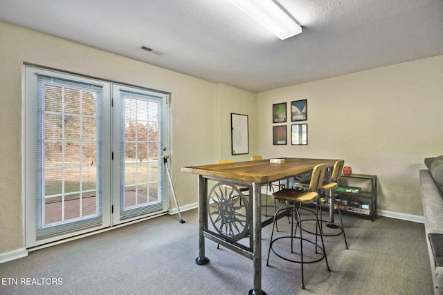 carpeted dining room with a textured ceiling