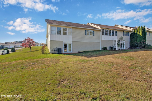 back of property featuring french doors, central AC unit, and a lawn