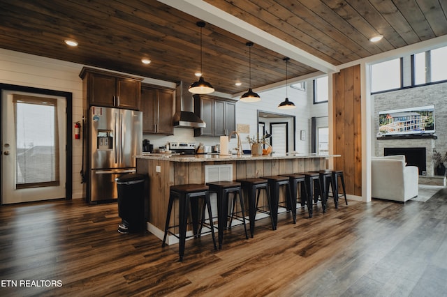 kitchen featuring wood ceiling, dark hardwood / wood-style floors, an island with sink, hanging light fixtures, and stainless steel appliances