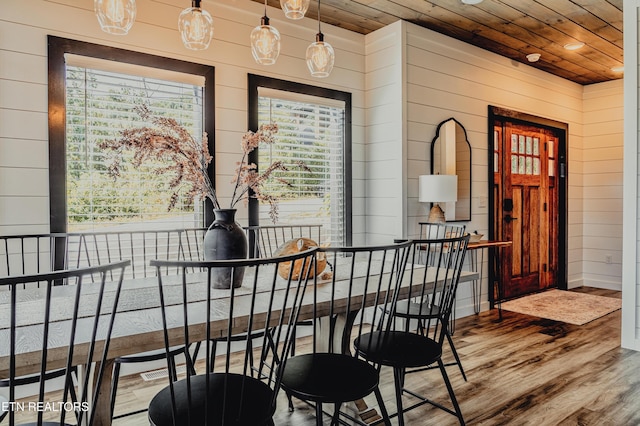 dining area featuring hardwood / wood-style flooring, wooden walls, and wooden ceiling