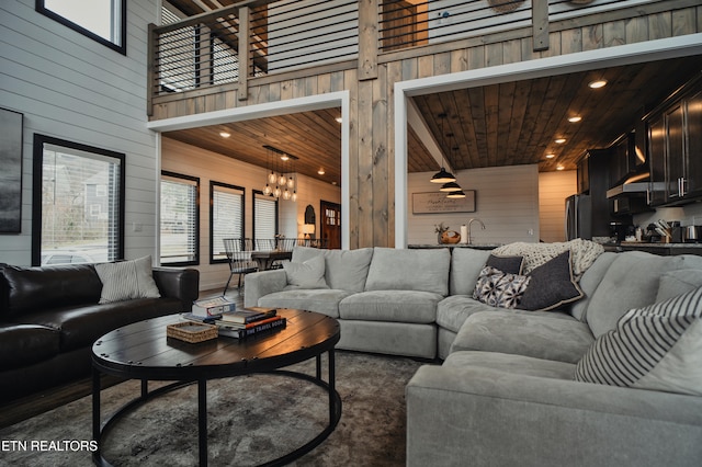 living room with a high ceiling, wood ceiling, and wood walls