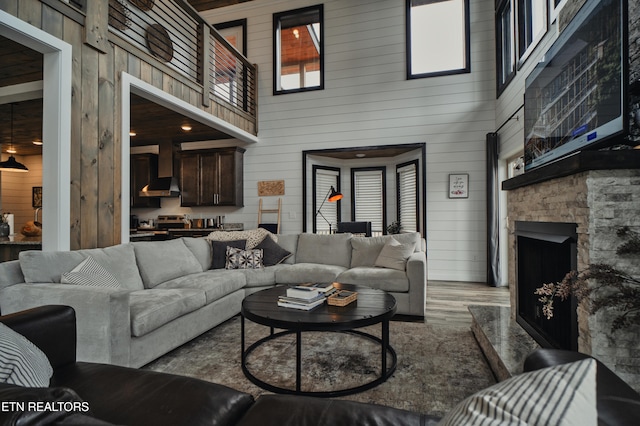 living room with a fireplace, wood walls, a high ceiling, and light wood-type flooring