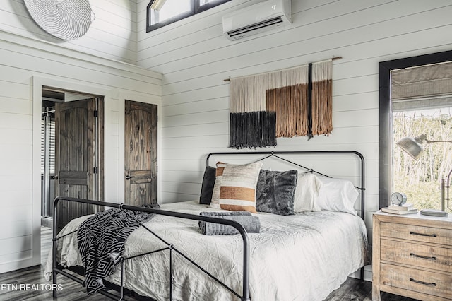 bedroom with a wall unit AC, wooden walls, and dark wood-type flooring