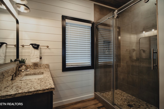 bathroom with vanity, wood walls, hardwood / wood-style flooring, and a shower with door