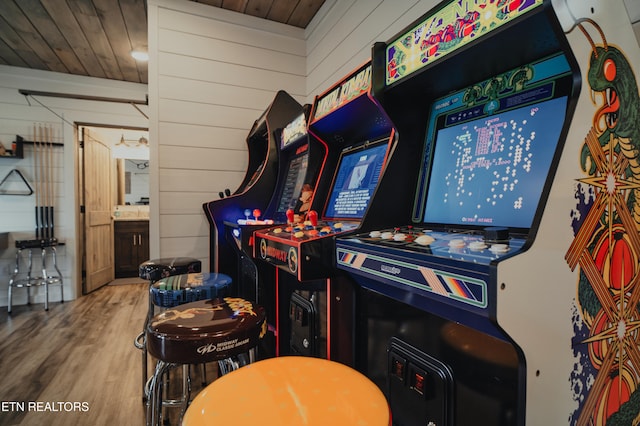 game room with ceiling fan, hardwood / wood-style flooring, wood ceiling, and wooden walls