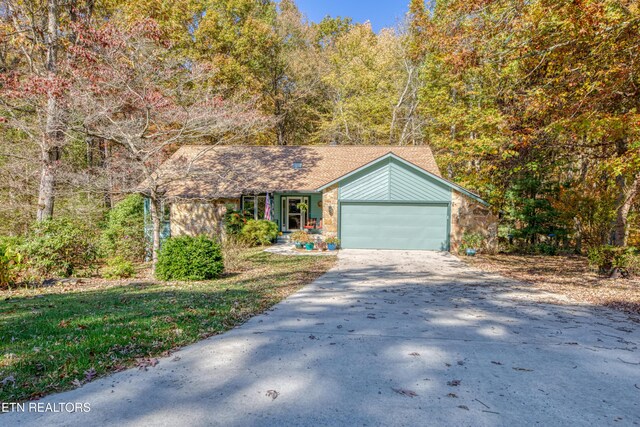 54 Heather Glen Ct, Crossville, TN 38558 - view of front of home featuring concrete driveway, an attached garage, stone siding, a wooded view, and roof with shingles