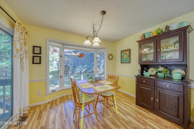 dining space with light hardwood / wood-style floors, a textured ceiling, and a wealth of natural light