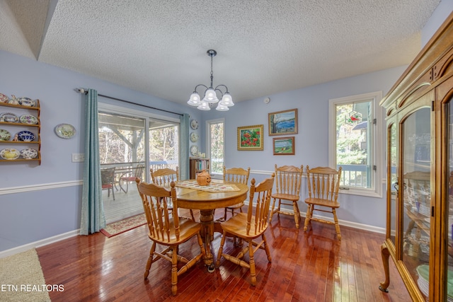 dining room featuring a notable chandelier, a textured ceiling, wood-type flooring, and plenty of natural light