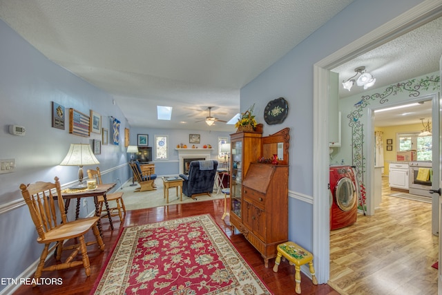 living room featuring washer / dryer, ceiling fan, a healthy amount of sunlight, and hardwood / wood-style floors