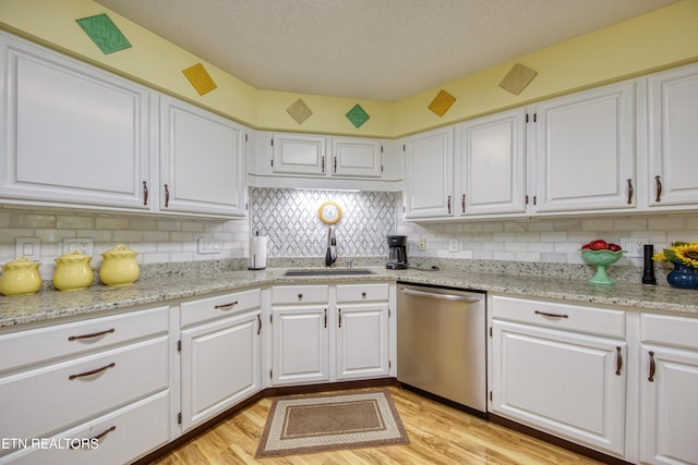 kitchen featuring light hardwood / wood-style flooring, white cabinetry, stainless steel dishwasher, and sink