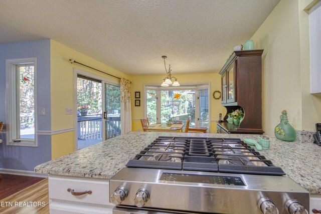 54 Heather Glen Ct, Crossville, TN 38558 - kitchen with stainless steel range with gas cooktop, wood finished floors, light stone countertops, a textured ceiling, and hanging light fixtures