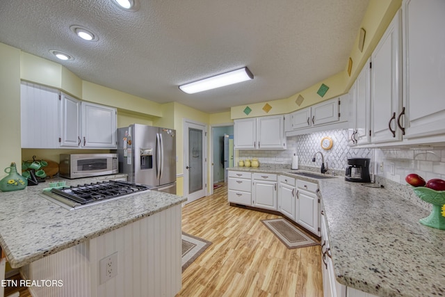 54 Heather Glen Ct, Crossville, TN 38558 - kitchen with appliances with stainless steel finishes, a sink, a peninsula, a textured ceiling, and light wood-type flooring