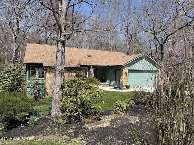 view of front facade with stone siding, driveway, a garage, and roof with shingles