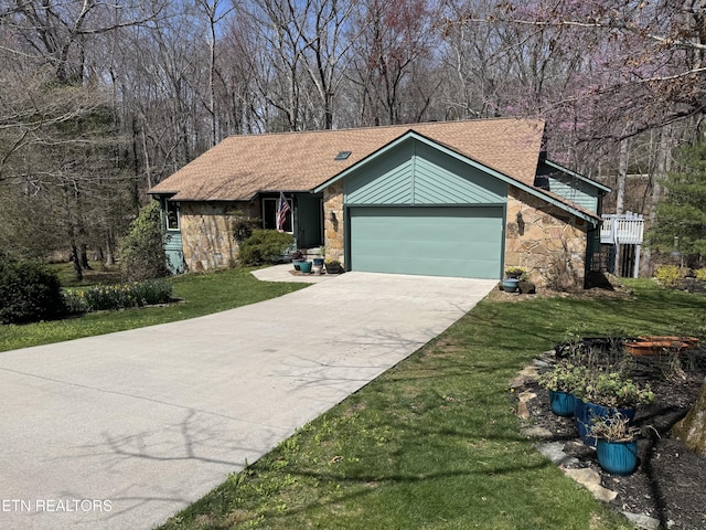 view of front of property with stone siding, a garage, concrete driveway, a front lawn, and a shingled roof