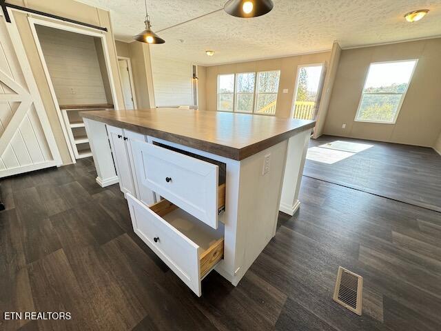 kitchen featuring a textured ceiling, decorative light fixtures, and white cabinets