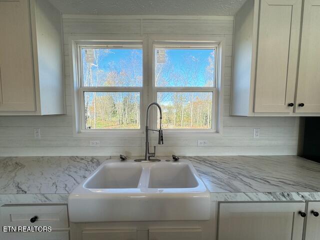 kitchen featuring a healthy amount of sunlight, decorative backsplash, sink, and white cabinets