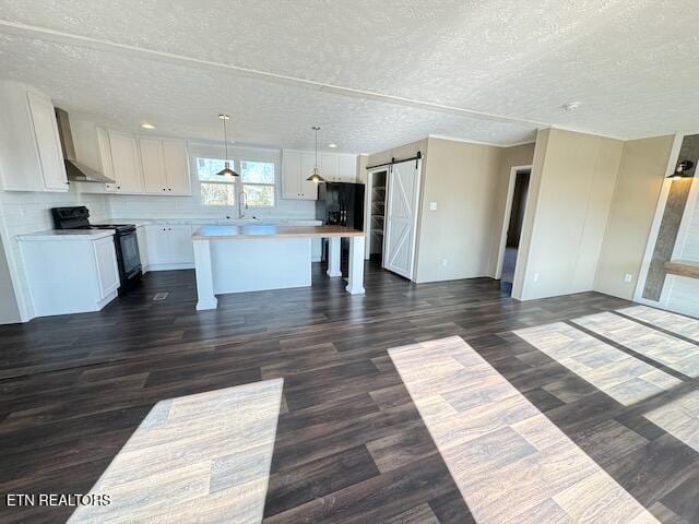 kitchen featuring black electric range, a barn door, a center island, dark hardwood / wood-style flooring, and white cabinetry